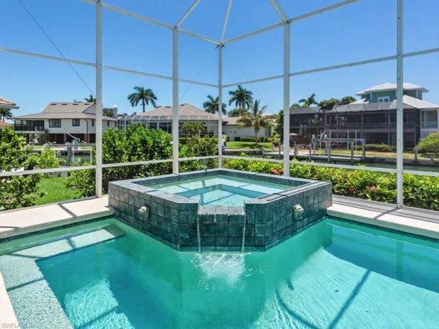 View of pool with a residential view, glass enclosure, and a pool with connected hot tub