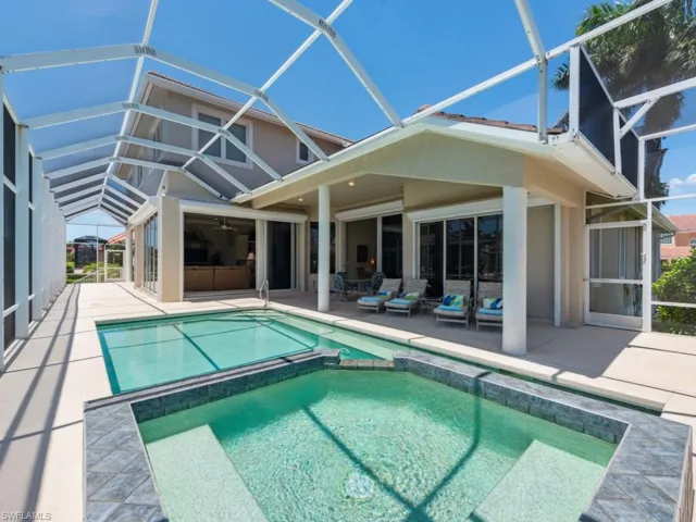 Back of house featuring a patio area, a lanai, and a pool with connected hot tub