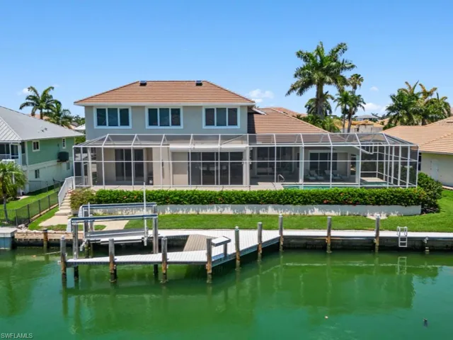 Back of property with a water view, a tile roof, and glass enclosure