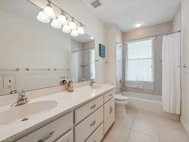 Full bath featuring tile patterned flooring, double vanity, shower / bath combo, and toilet