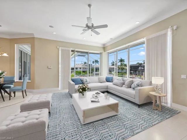Living area with healthy amount of natural light, ceiling fan, tile patterned flooring, baseboards, and crown molding