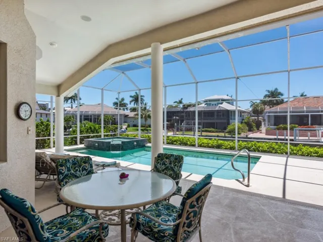 View of pool with a residential view, a patio area, glass enclosure, and a pool with connected hot tub