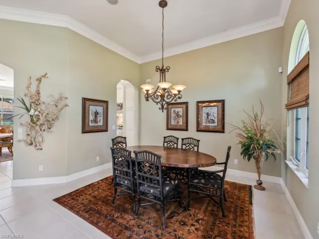 Dining space with crown molding, light tile patterned floors, a chandelier, arched walkways, and baseboards