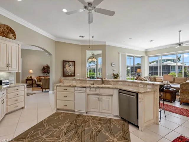Kitchen with stainless steel dishwasher, a ceiling fan, open floor plan, light tile patterned floors, and plenty of natural light