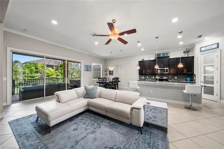 Living room featuring ceiling fan, ornamental molding, and light tile flooring