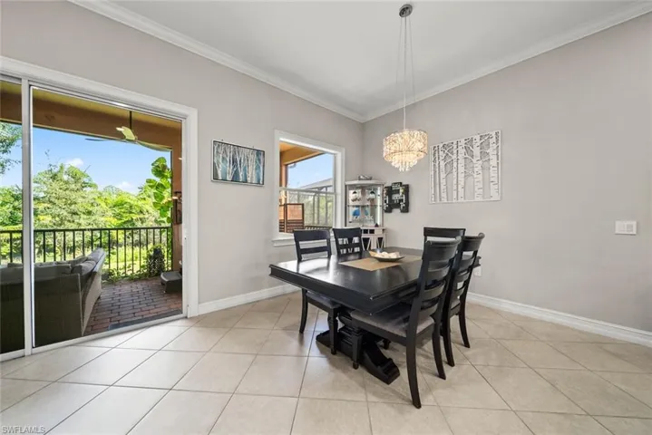 Dining room with crown molding, an inviting chandelier, and light tile flooring