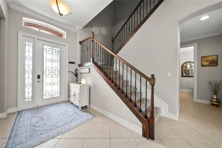 Foyer entrance featuring crown molding and light tile patterned flooring