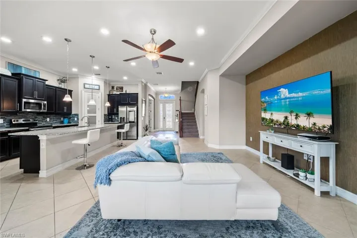 Living room featuring ceiling fan, crown molding, and light tile patterned flooring