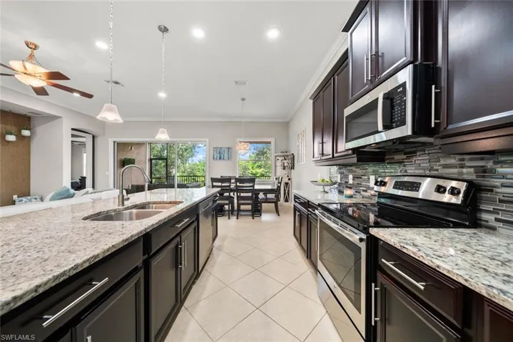Kitchen with decorative backsplash, appliances with stainless steel finishes, sink, ceiling fan, and pendant lighting