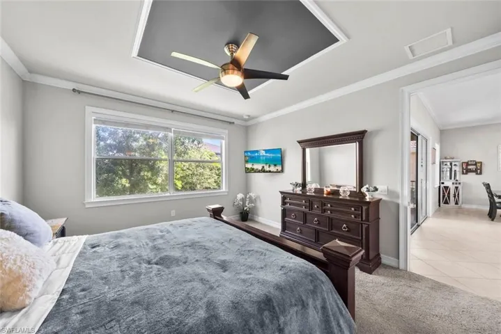 Primary Bedroom with ceiling fan, light tile patterned floors, and crown molding