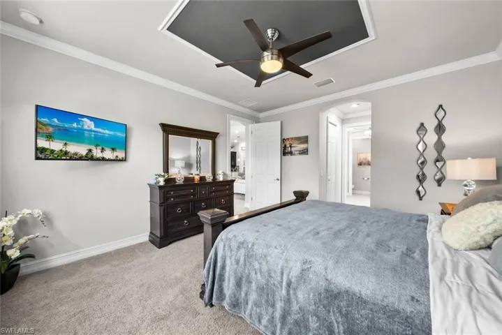 Primary Bedroom featuring light colored carpet, ceiling fan, and ornamental molding