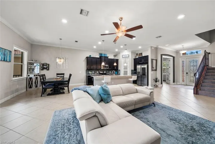 Tiled living room featuring a wealth of natural light, crown molding, and ceiling fan