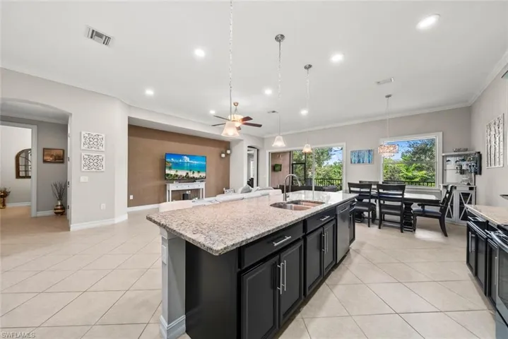 Kitchen with a kitchen island with sink, crown molding, decorative light fixtures