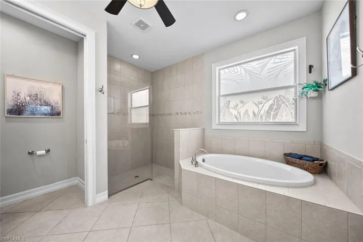 Primary Bathroom with tile patterned floors, independent shower and bath, plenty of natural light, and ceiling fan