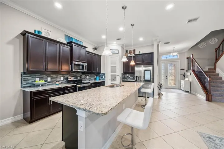 Kitchen featuring a center island with sink, pendant lighting, a kitchen bar, stainless steel appliances