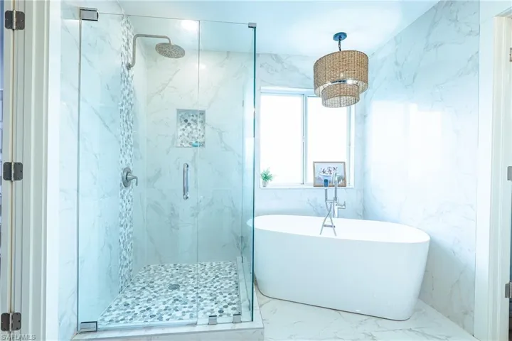 Master bathroom featuring a soaking tub, marble finish floor, and a marble finish shower