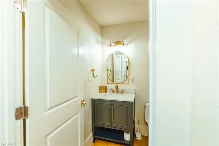 Half bathroom with wood finished floors, toilet, and vanity
