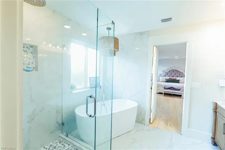 Master bathroom with marble finish floor, a freestanding tub, vanity, and a marble finish shower