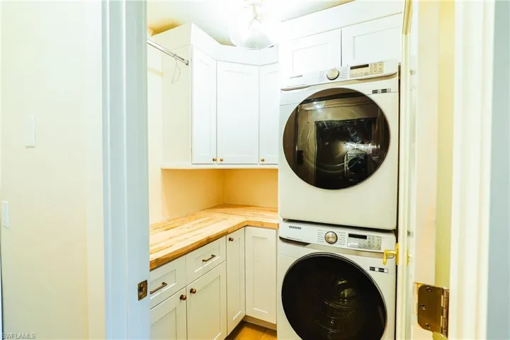 Laundry area featuring stacked washer / dryer and cabinet space