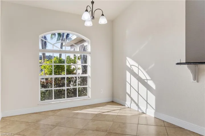 Unfurnished dining area featuring light tile patterned flooring and a notable chandelier