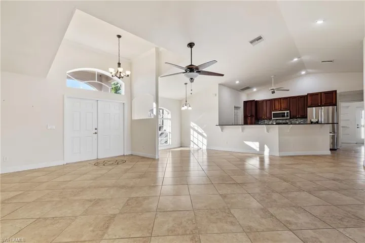 Tiled foyer entrance with ceiling fan with high vaulted ceiling