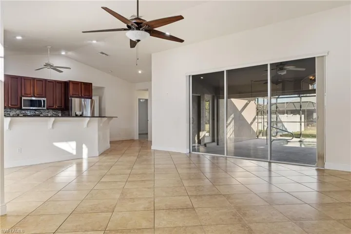Unfurnished living room with light tile patterned floors and vaulted ceiling