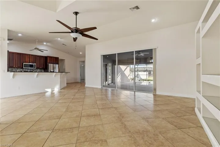 Unfurnished living room with light tile patterned floors and vaulted ceiling