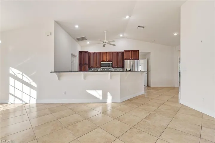 Kitchen with kitchen peninsula, a kitchen breakfast bar, appliances with stainless steel finishes, ceiling fan, and lofted ceiling