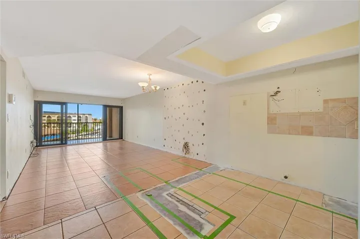 Tiled spare room with a chandelier and baseboards