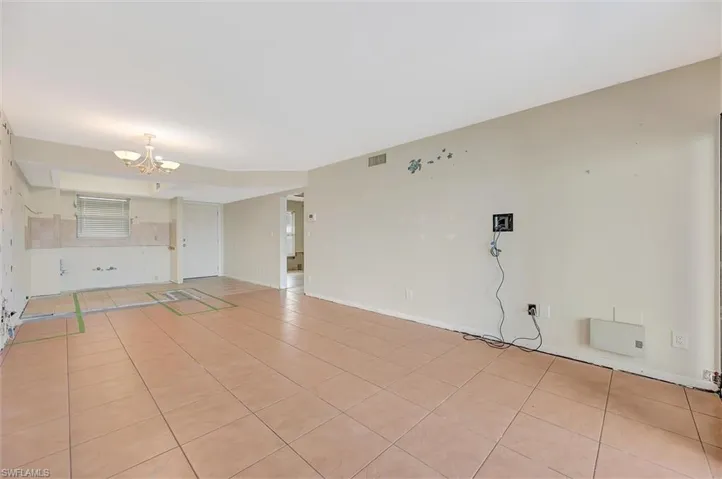 Unfurnished living room with light tile patterned flooring and a chandelier