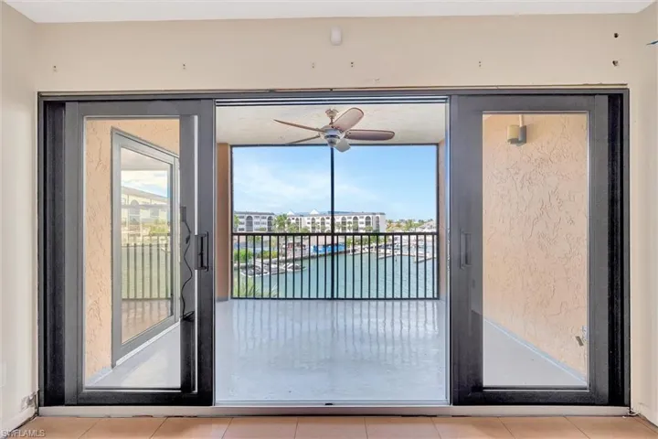 Doorway with a water view, a ceiling fan, and tile patterned floors