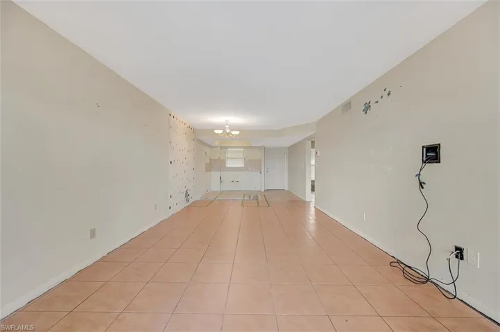 Unfurnished living room featuring a chandelier and light tile patterned flooring