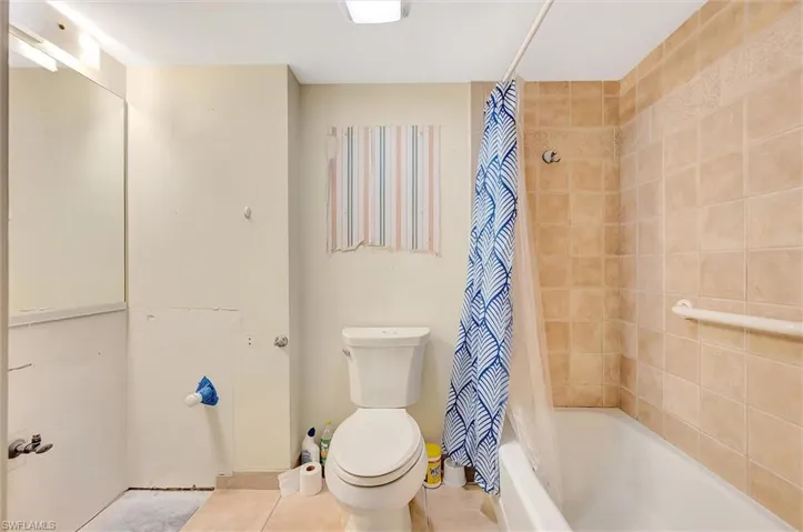 Full bathroom featuring shower / tub combo with curtain and tile patterned flooring