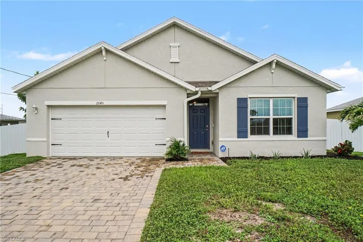 Contemporary stucco exterior featuring a two-car garage, paver driveway, dark blue shutters, and a matching dark blue entry door