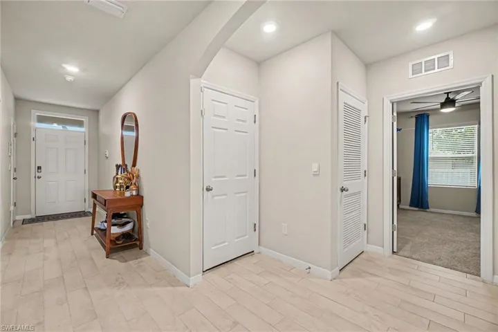 Entryway featuring light-toned plank flooring, recessed ceiling lighting, and a paneled front door with sidelight