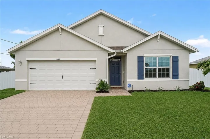 Stucco exterior with a paver driveway, an attached garage, a blue entry door, and matching blue decorative shutters