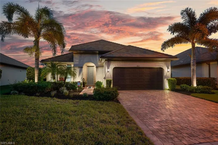 Front Elevation featuring decorative driveway, a garage, a front lawn, stucco siding, and a tiled roof
