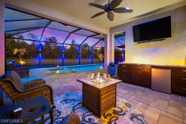 View of patio / terrace featuring screen enclosure, a ceiling fan, a sunroom, an outdoor pool, and exterior kitchen