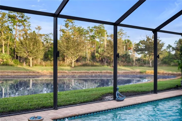 Swimming pool with a lawn, screen enclosure, a water view, and a sunroom