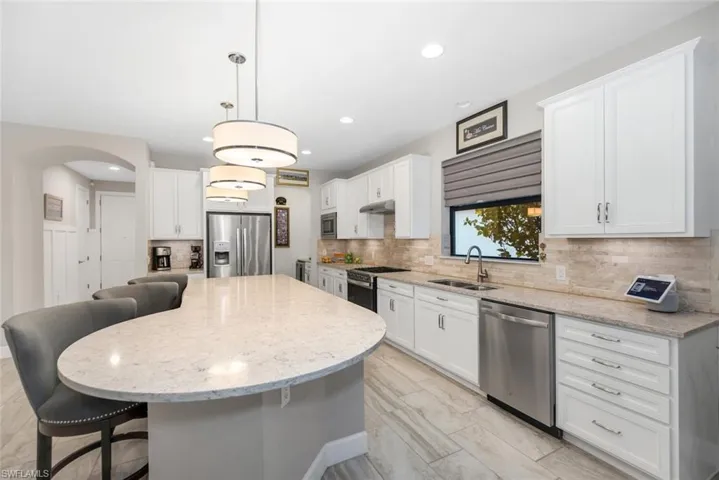 Kitchen with white cabinetry, stainless steel appliances, light stone counters, and recessed lighting