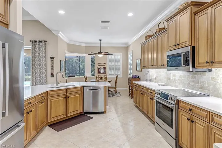 Kitchen featuring appliances with stainless steel finishes, sink, light tile flooring, and ceiling fan
