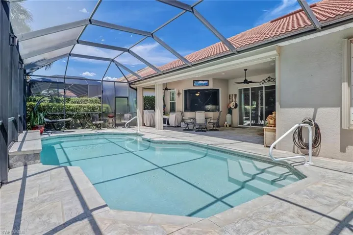 View of swimming pool with a patio, glass enclosure, and ceiling fan