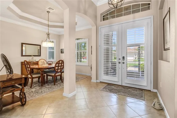 Tiled entrance foyer with plenty of natural light, ornamental molding, french doors, and a tray ceiling