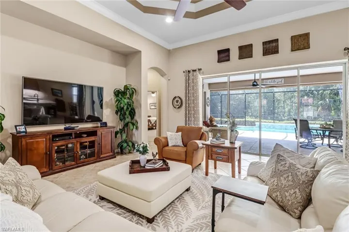Living room with ceiling fan, crown molding, and light tile floors