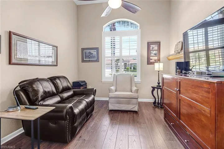 Living room with a high ceiling, ceiling fan, and dark hardwood / wood-style flooring