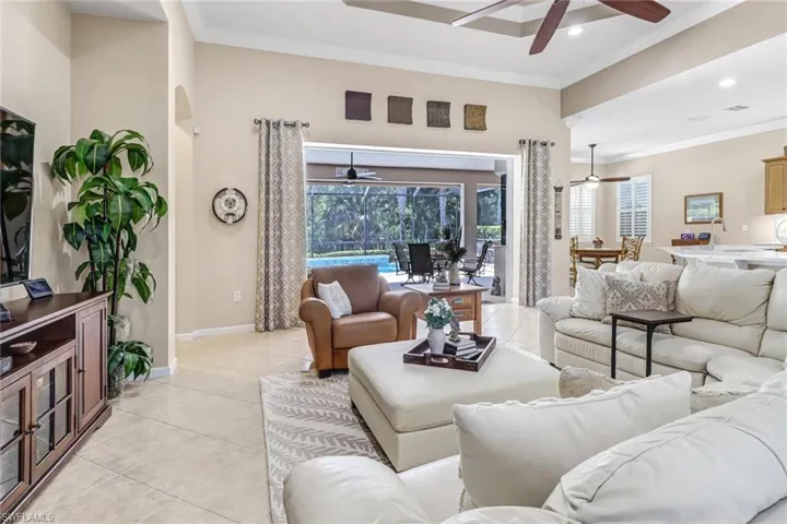 Living room featuring ornamental molding, light tile flooring, and ceiling fan