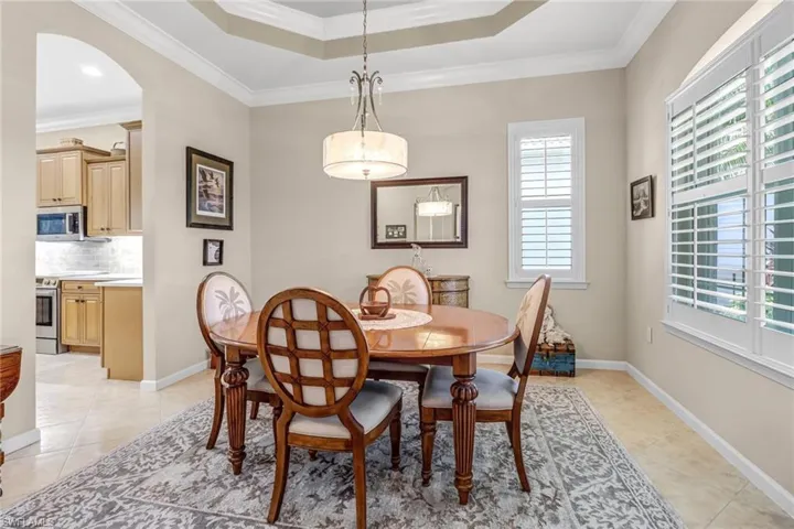 Dining space with crown molding, plenty of natural light, light tile floors, and a raised ceiling