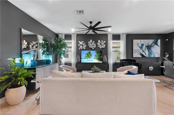 Spacious living area featuring contemporary dark gray walls and light wood-finish flooring