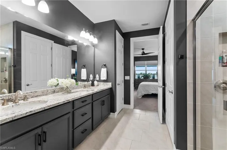 Bathroom featuring a dual vanity with undermount sinks, stone-finish countertop, dark wood-finish cabinetry, and brushed nickel fixtures