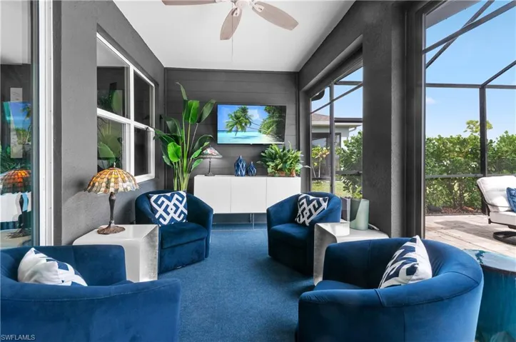 Screened outdoor living area featuring a ceiling fan, wall-mounted television, and a built-in white console